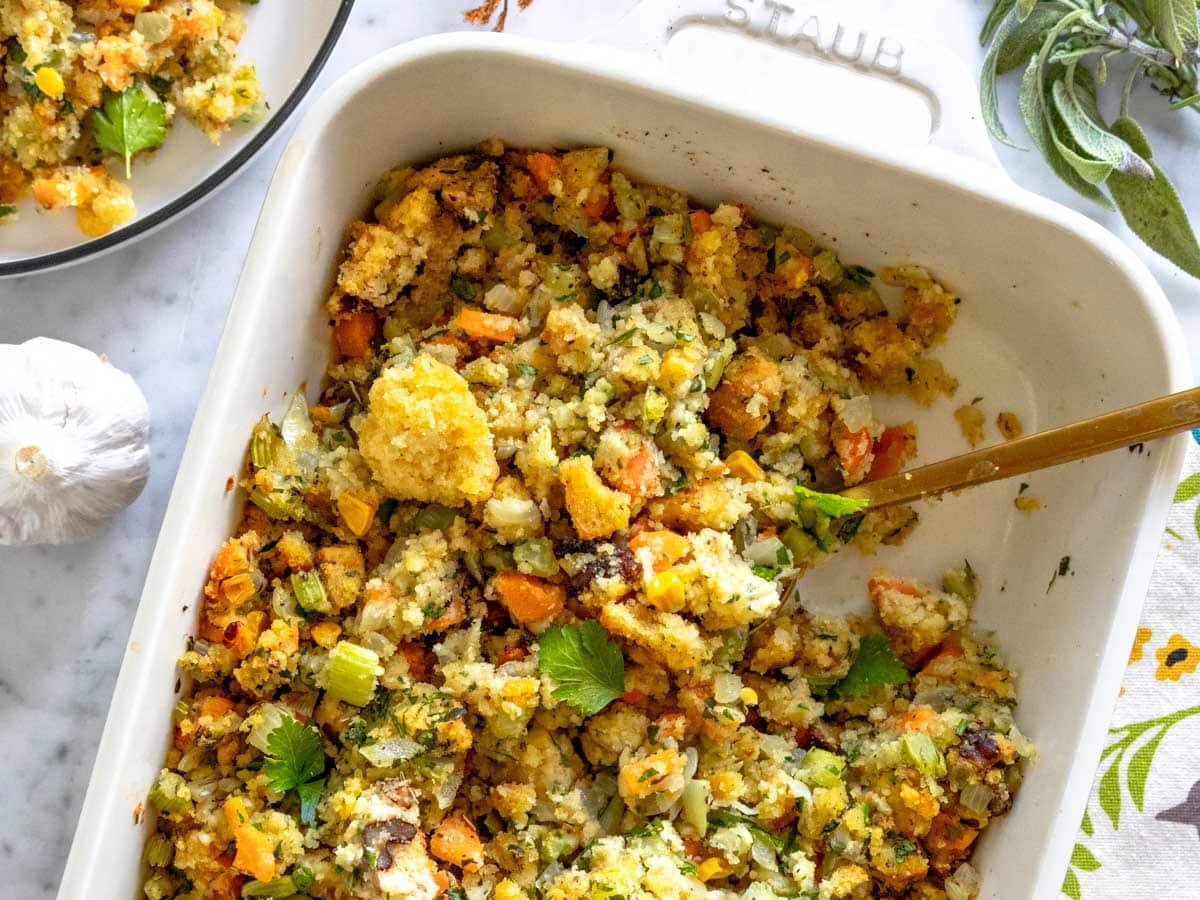 Cornbread stuffing with a golden spoon and fresh herbs