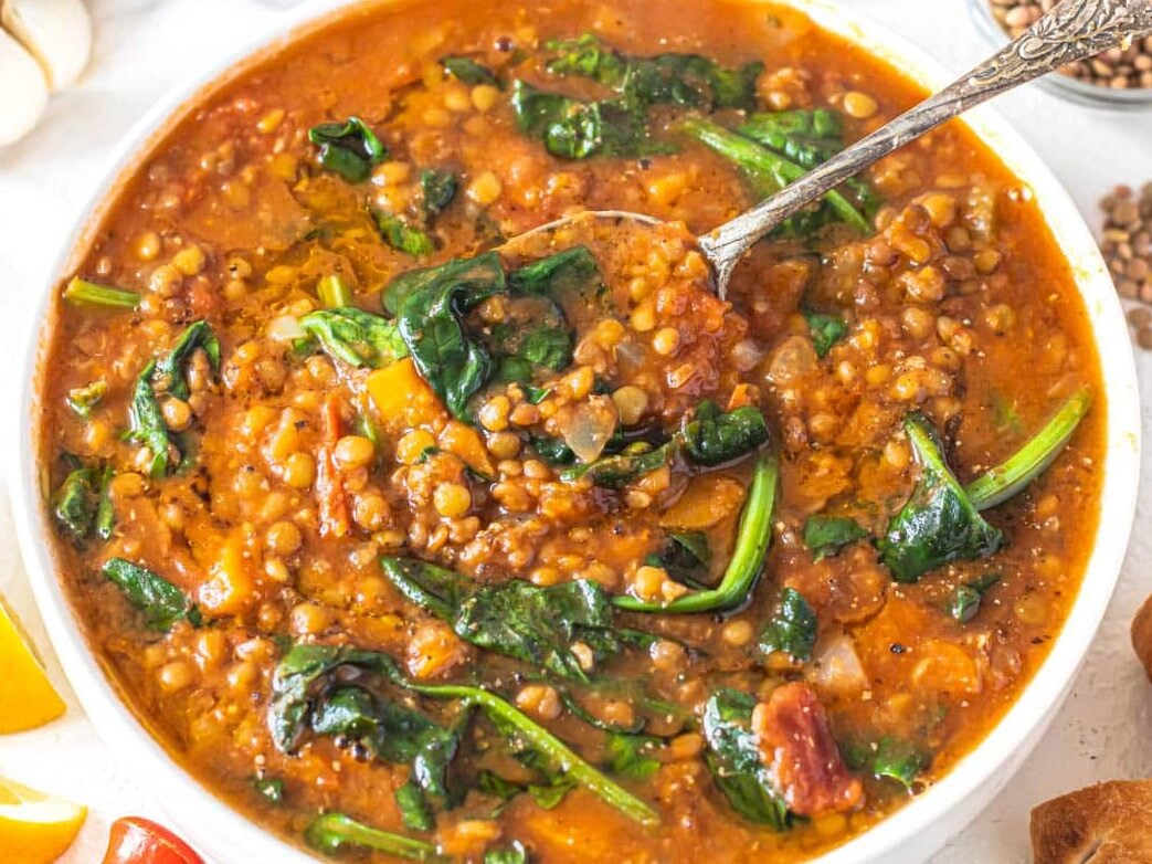 Easy lentil vegetable soup with spinach leaves and pita bread on the side