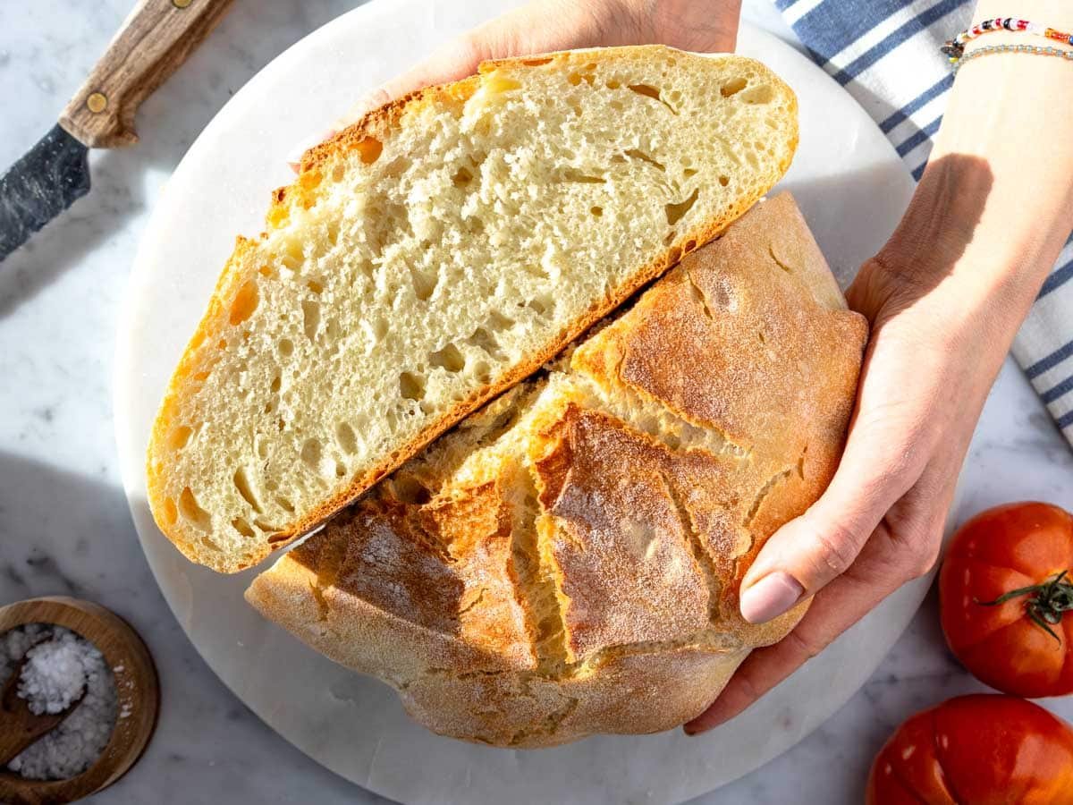 female hands holding a homemade artisan bread with perfect golden crust