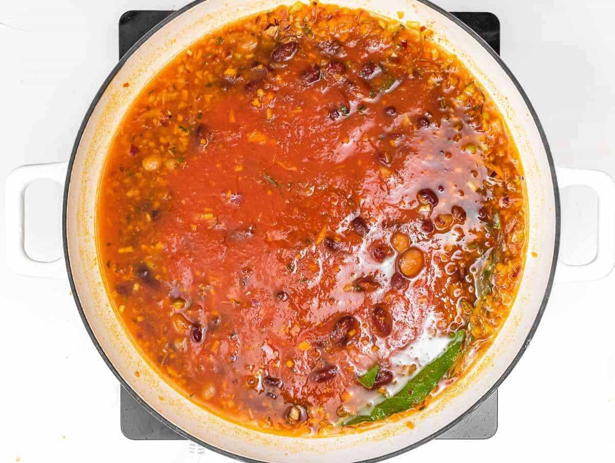 Step 2 Beans broth and tomatoes simmering in pot for homemade pasta e fagioli soup.