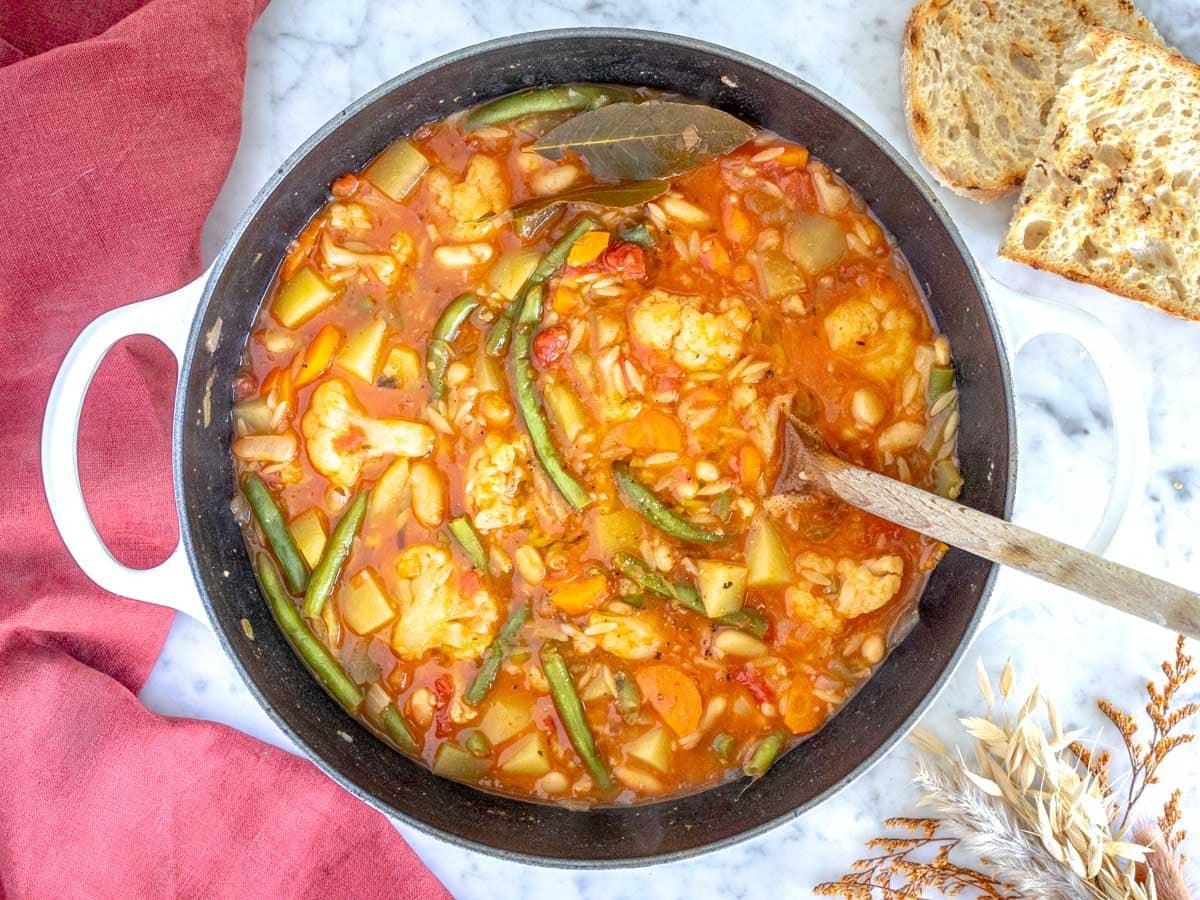 vegetable soup with orzo pasta and green beans in a large pot.