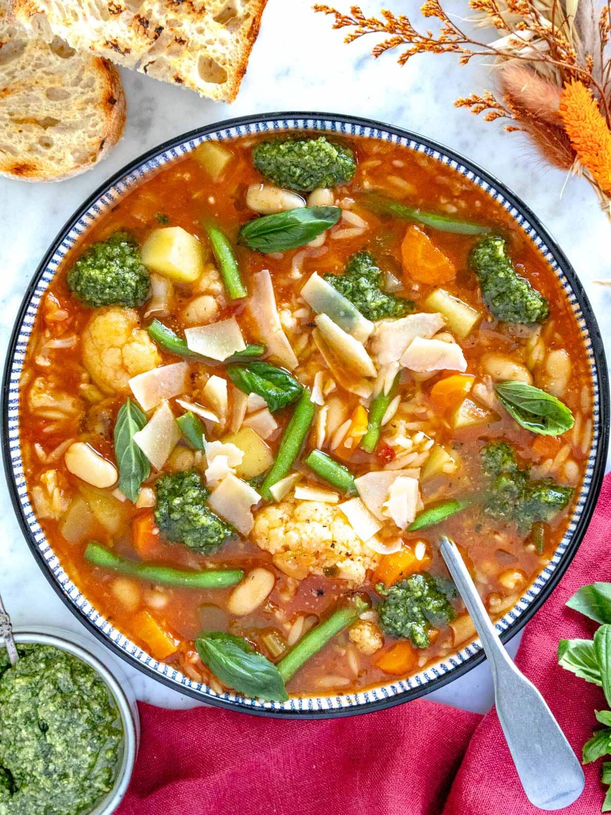 Vegetable soup with green pesto and a silver spoon