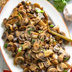 sauteed mushrooms with a golden spoon and fresh parsley