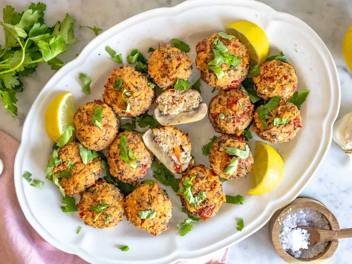 stuffed mushrooms on a white platter with fresh parsley