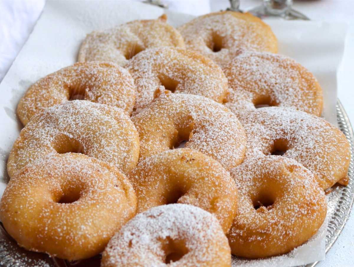 vegan apple fritters on a silver platter with powdered sugar