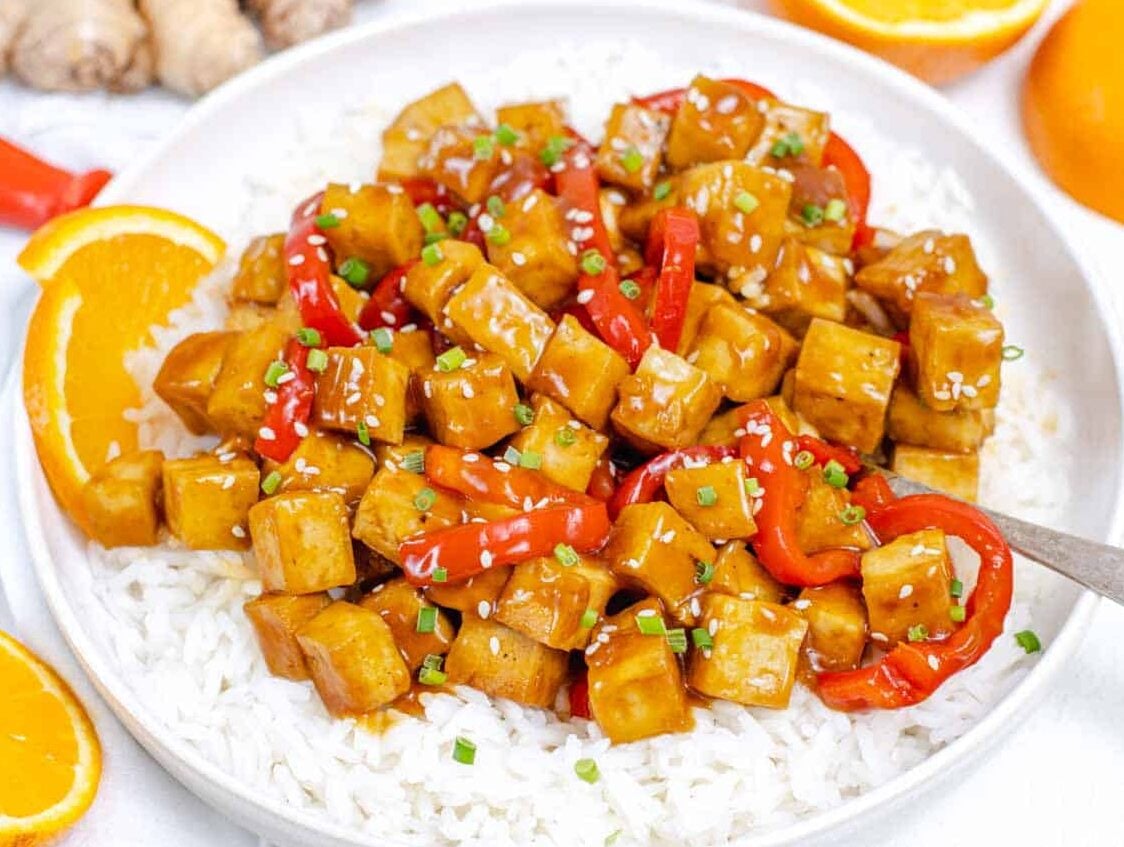 Orange Tofu on a plate with rice and a spoon