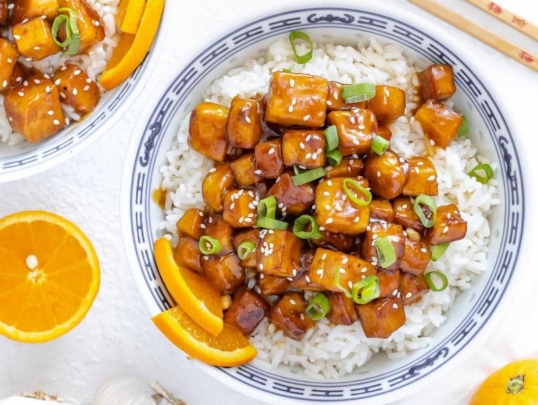 orange tofu served with rice and green onion on top