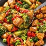 Orange tofu and broccoli over rice with glossy citrus sauce.
