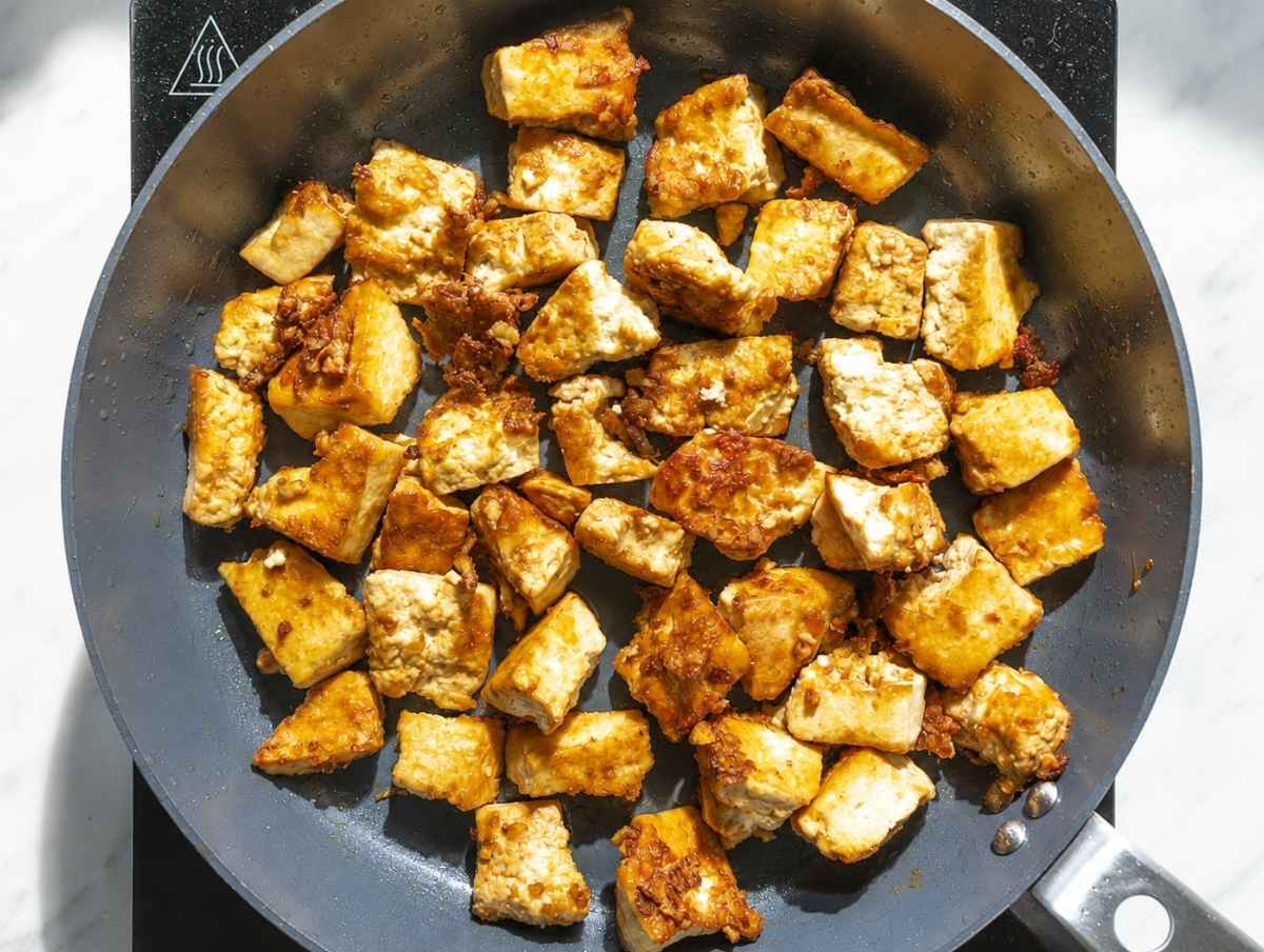 Step 1 Cornstarch-coated tofu chunks pan-frying until crisp and golden.