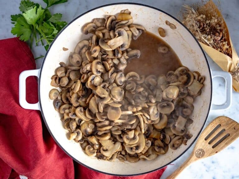 chopped mushrooms in a white skillet releasing water