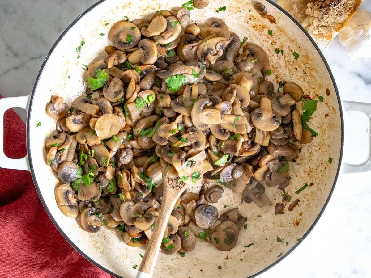 sauteed mushrooms with parsley in a white skillet