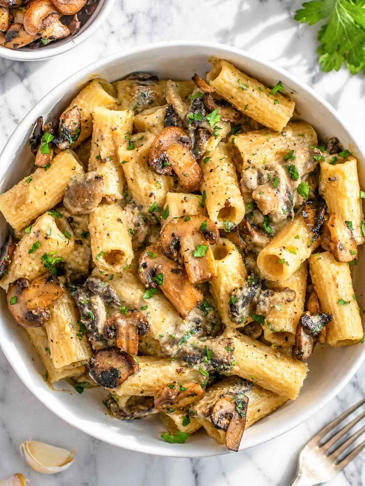 Creamy hummus pasta with browned mushrooms, parsley, Parmesan, and black pepper.