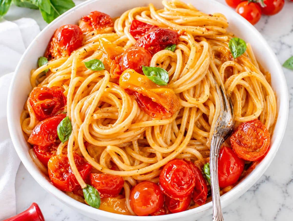 Glossy cherry tomato pasta with Parmesan and basil in natural light.