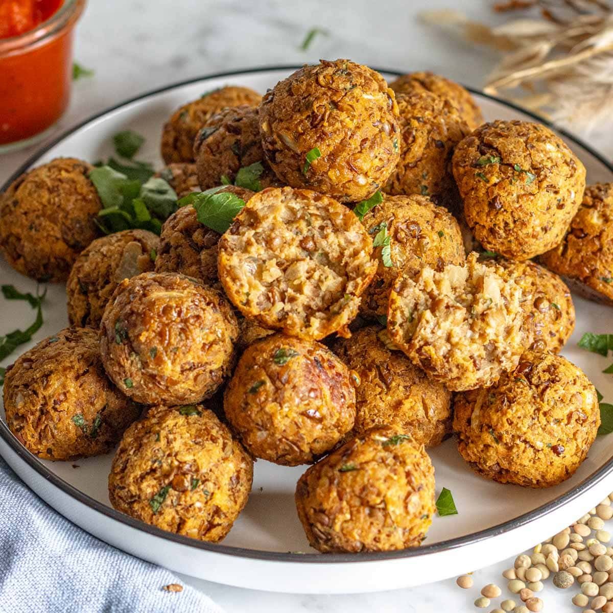 Lentil meatballs on a white plate with a bite.