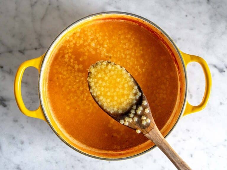 Creamy pastina soup in a yellow cast iron pot.