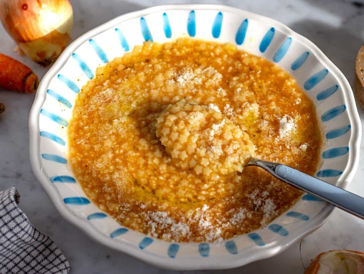 Pastina soup with grated parmesan cheese and a spoon.