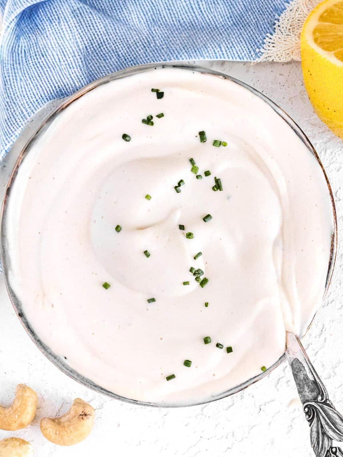 Vegan sour cream with cashews and a silver spoon.