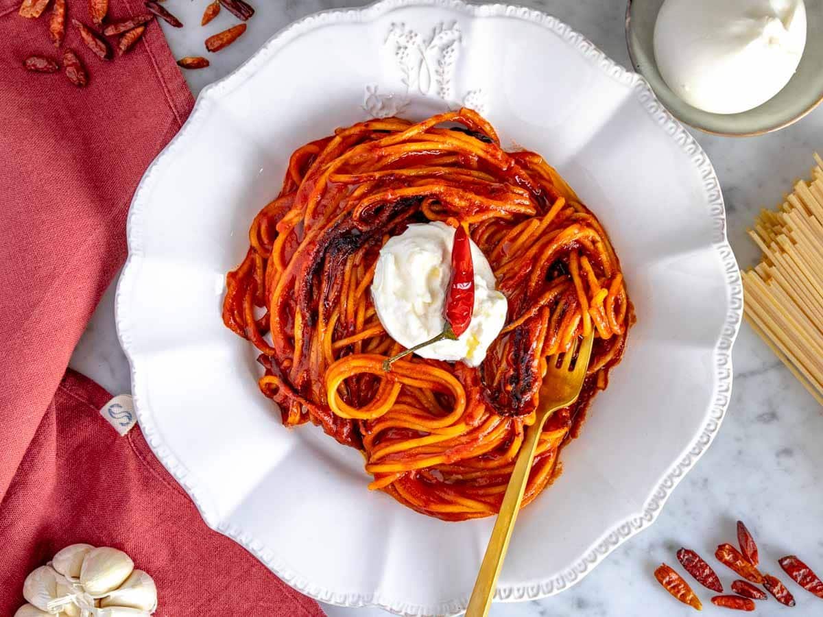 Assassin's spaghetti with a golden fork on a white plate.