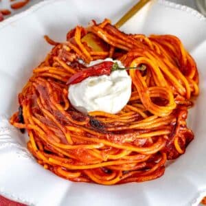 assassin's spaghetti in a white bowl with burrata cheese.