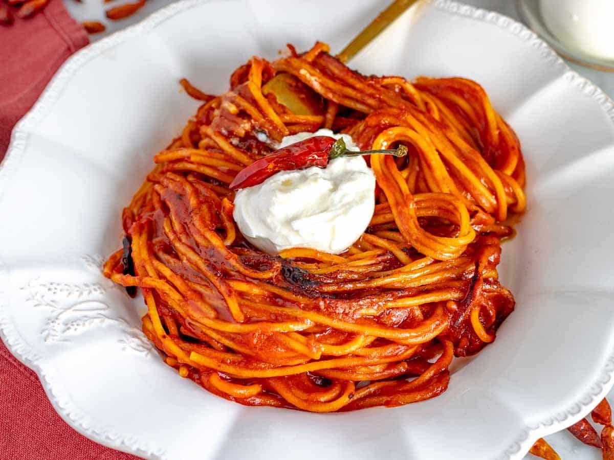 assassin's spaghetti on a white plate with chili and a golden fork.