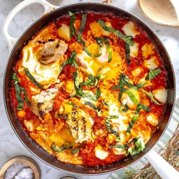 eggs in purgatory in a white skillet with basil.