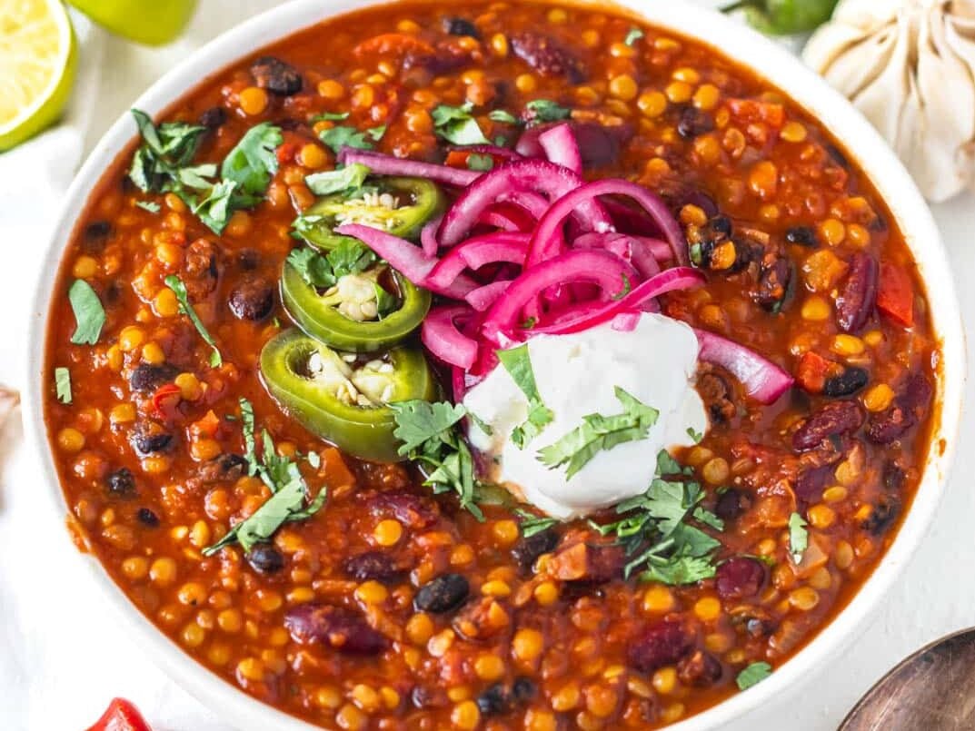 lentil chili with sour cream and pickled jalapenos in a bowl