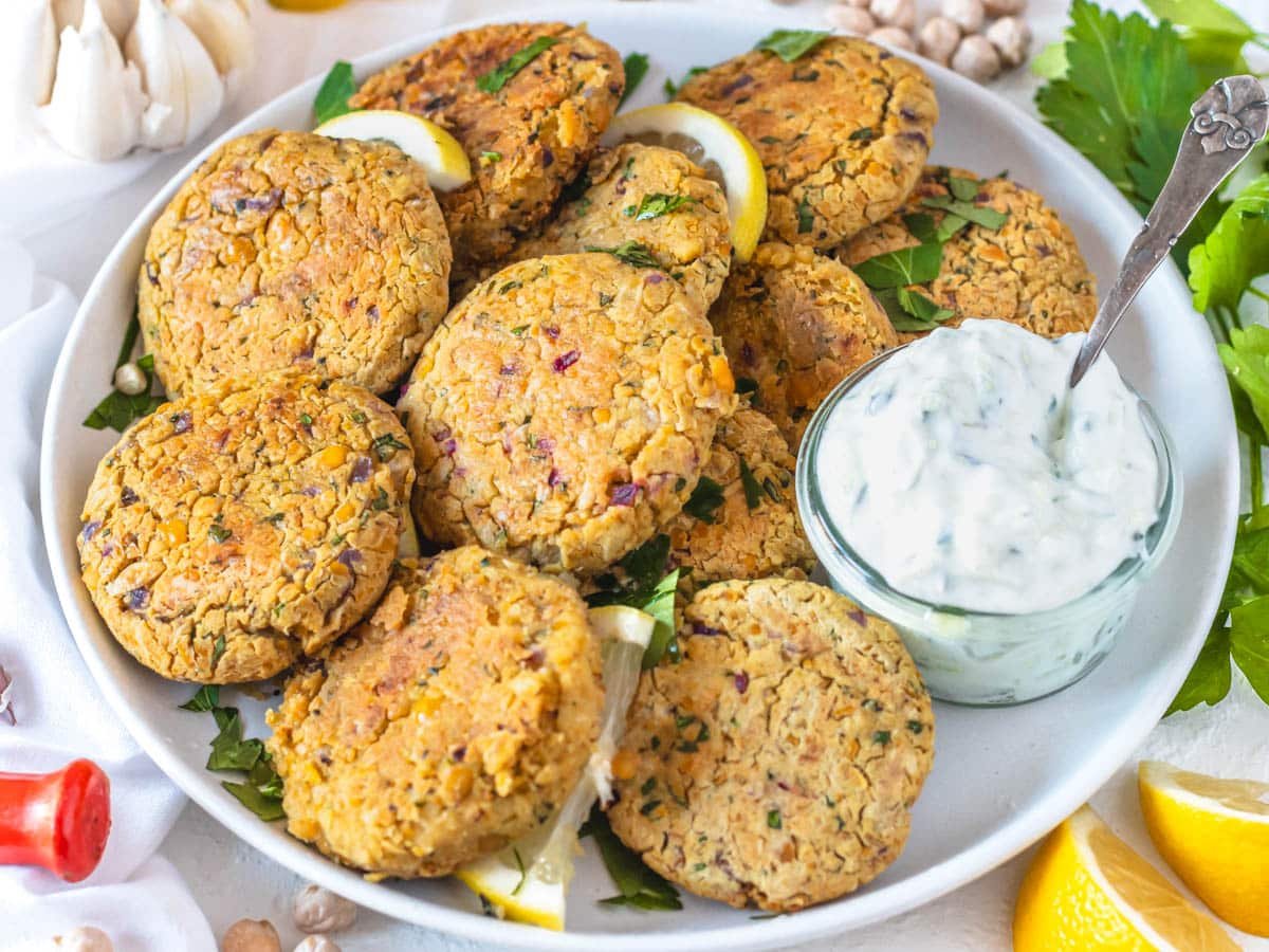 Chickpea fritters in a plate served with tzatziki sauce.