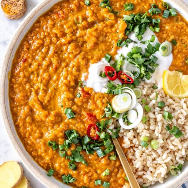 Creamy lentil curry with rice, yogurt, cilantro, and lemon on a bright marble surface.