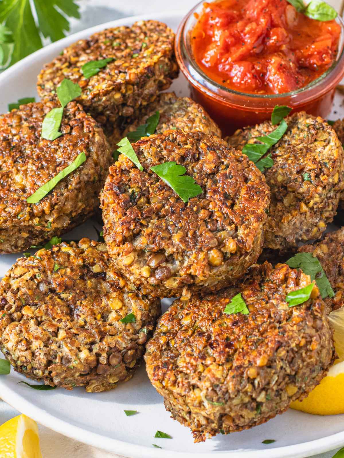 Golden lentil patties with crisp edges, parsley, and lemon wedges on a plate.