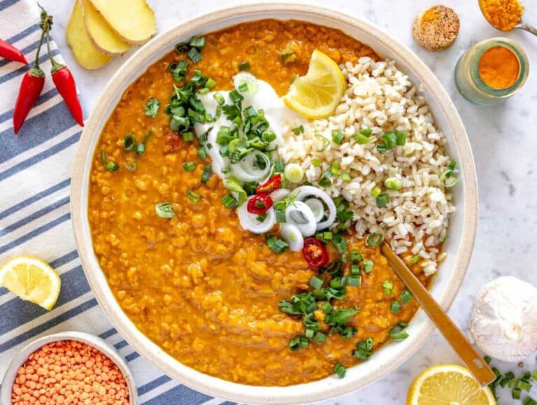 Lentil curry in a bowl served with rice, yogurt, lemon juice, and cilantro.