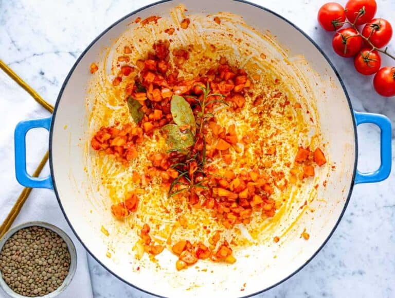 Making the flavor base with onion, carrot, and tomato paste in a skillet.