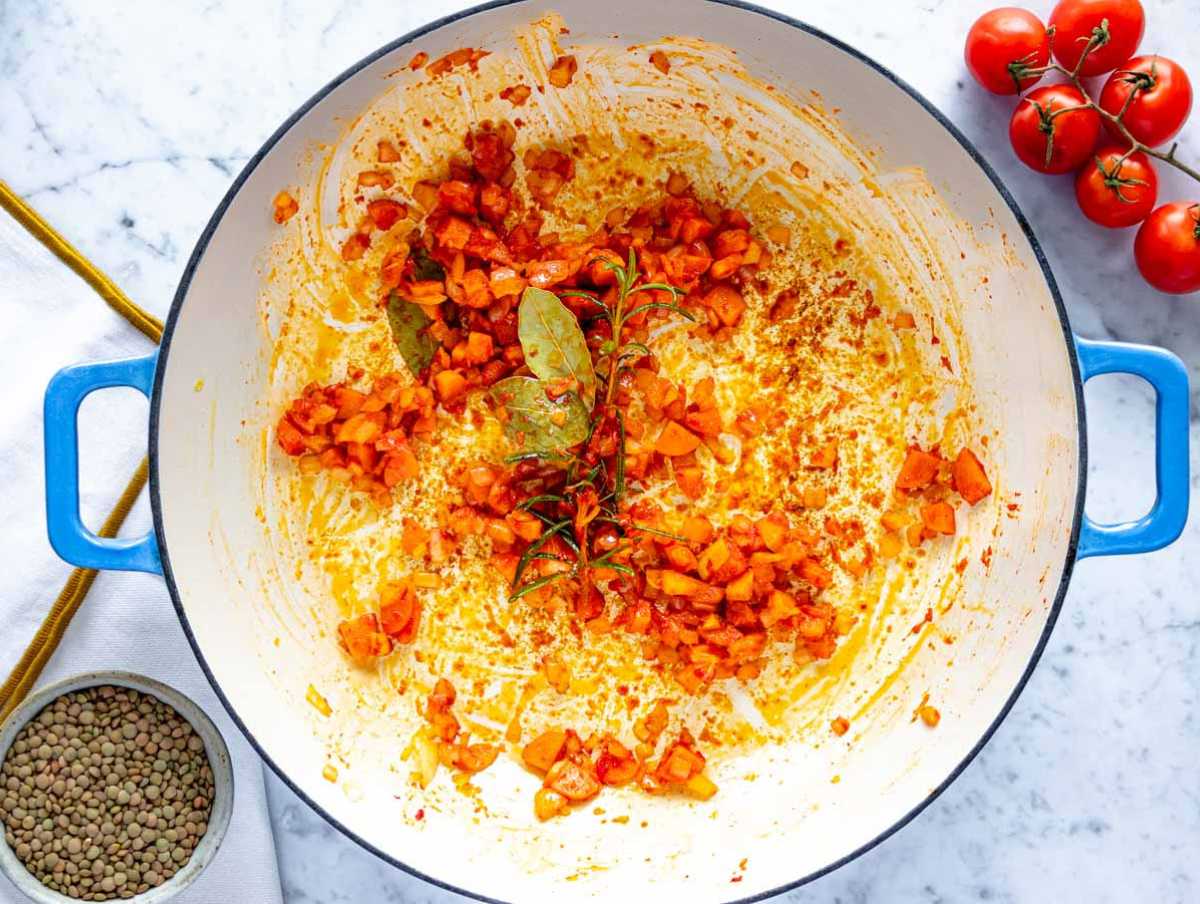 Making the flavor base with onion, carrot, and tomato paste in a skillet.
