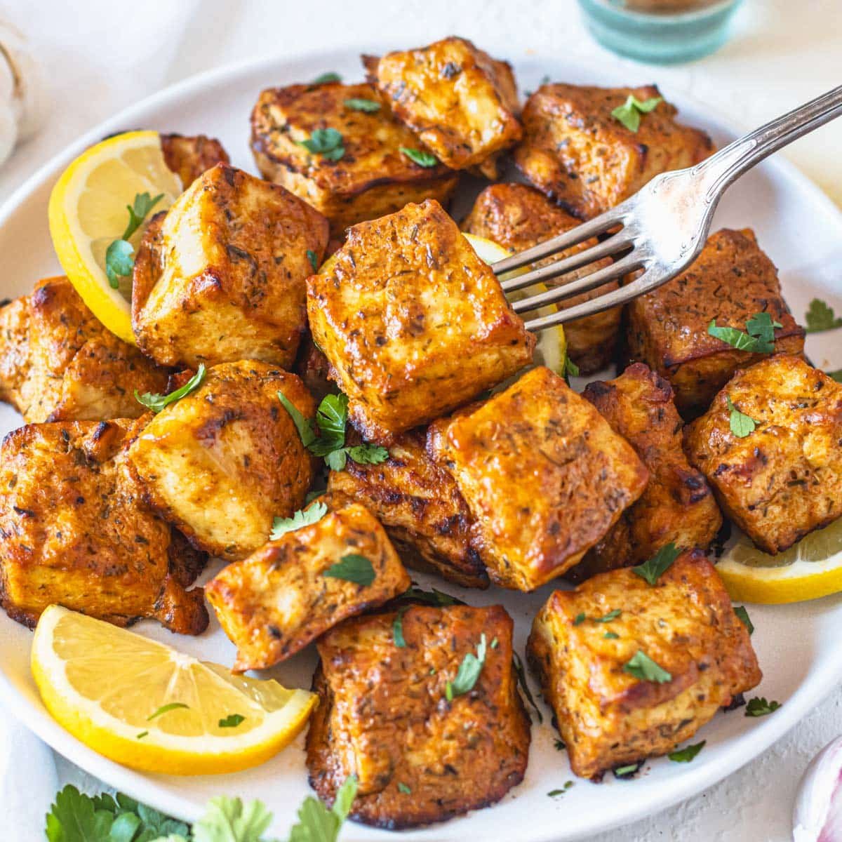 Marinated tofu with lemon slices and a silver fork.