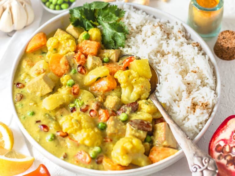 Navratan Korma served in a bowl with rice and lemon juice.