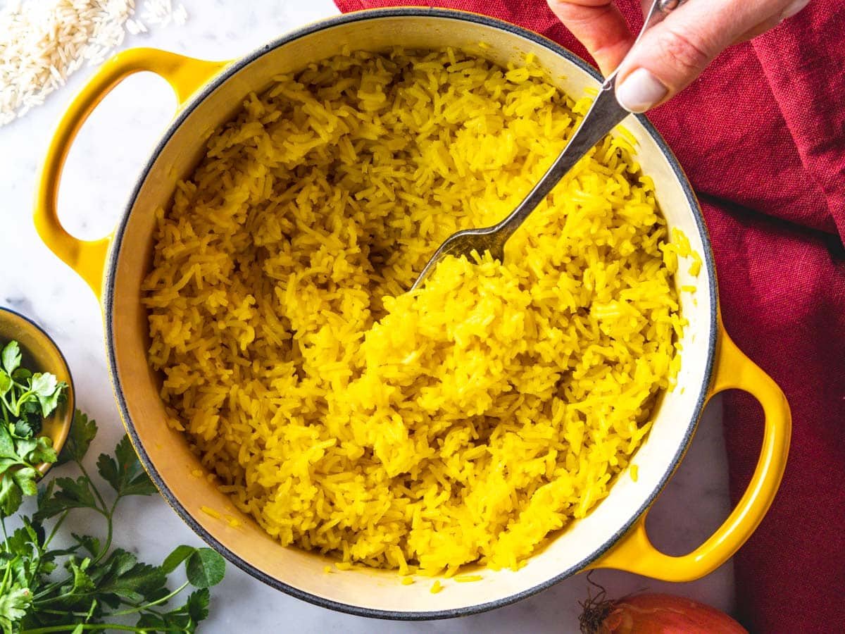 Female hand with a fork in saffron rice.