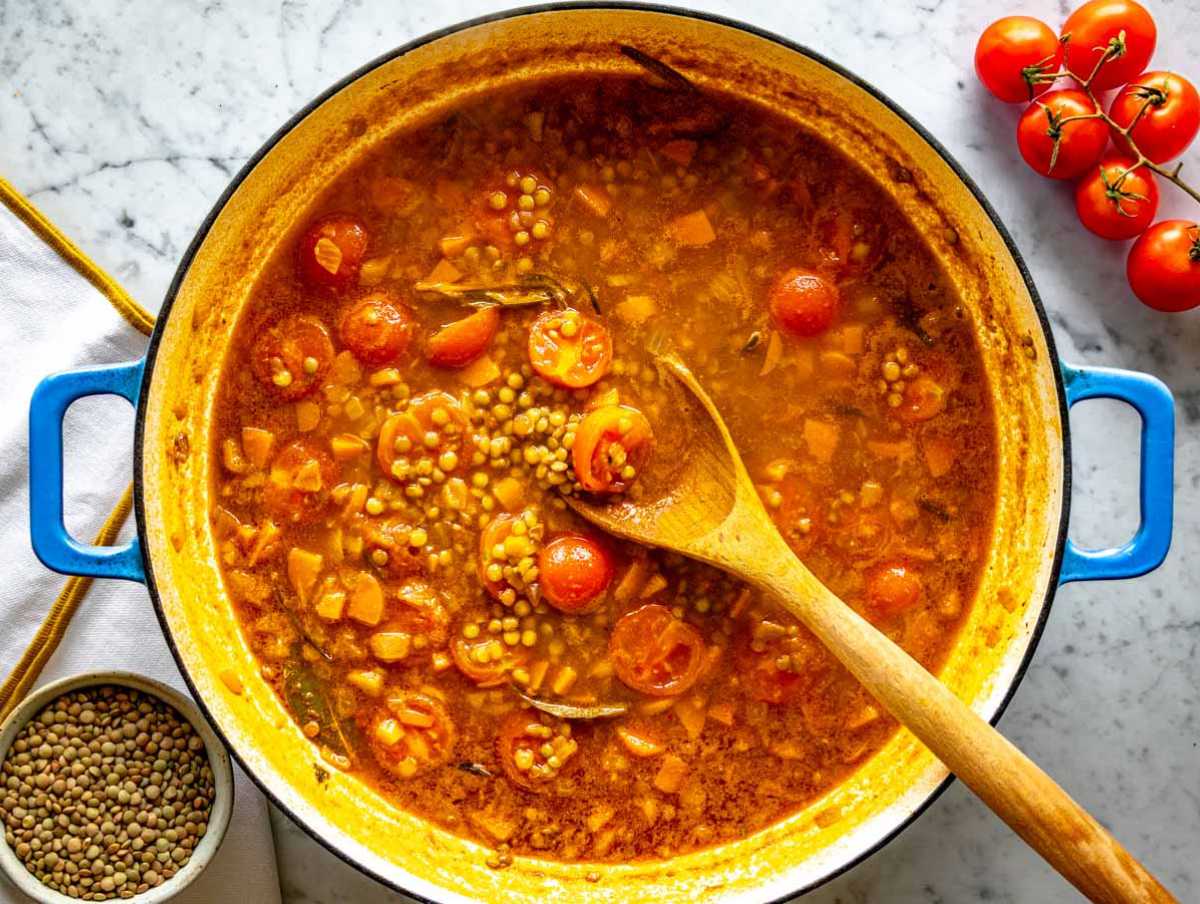 Simmering the lentils in broth with tomatoes.