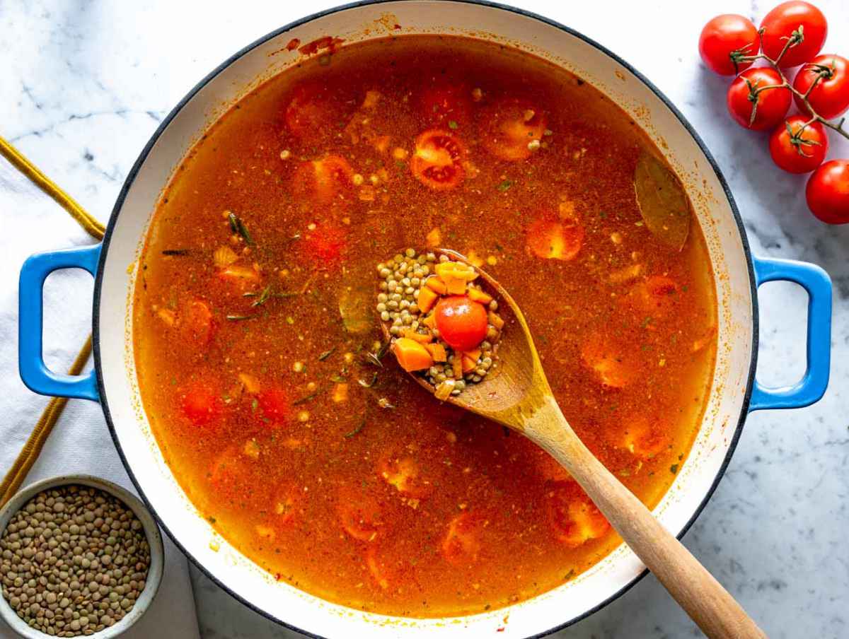 Step 2 Lentils and cherry tomatoes simmering with herbs in savory vegetable broth.