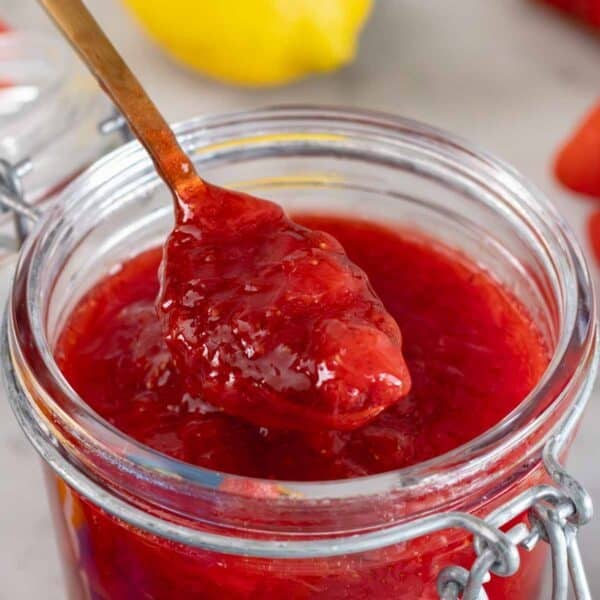 A teaspoon of strawberry jam in a glass jar.