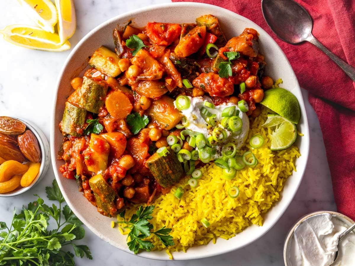 Tagine served in a bowl with saffron rice, yogurt, parsley, and lime juice.