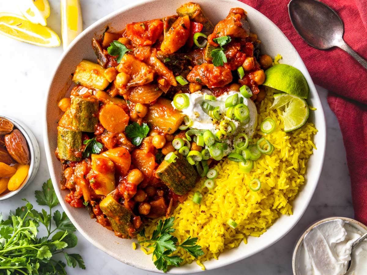 Tagine recipe in a white bowl with saffron rice and lime.