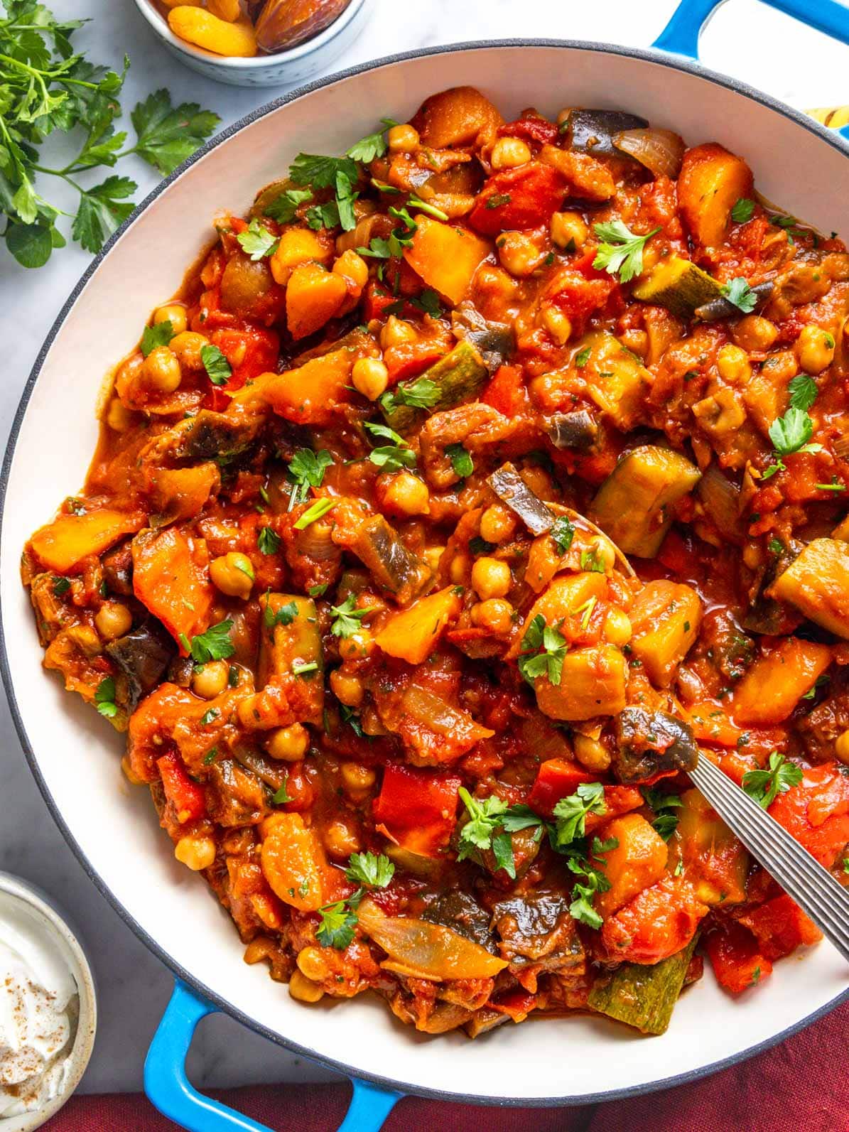 Tagine with chickpeas and vegetables and a silver spoon.