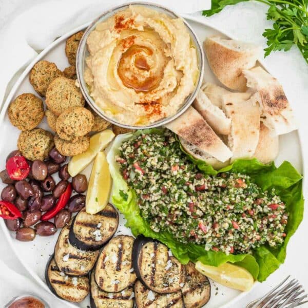 Hummus, falafel, tabbouleh, and grilled eggplant on a plate.