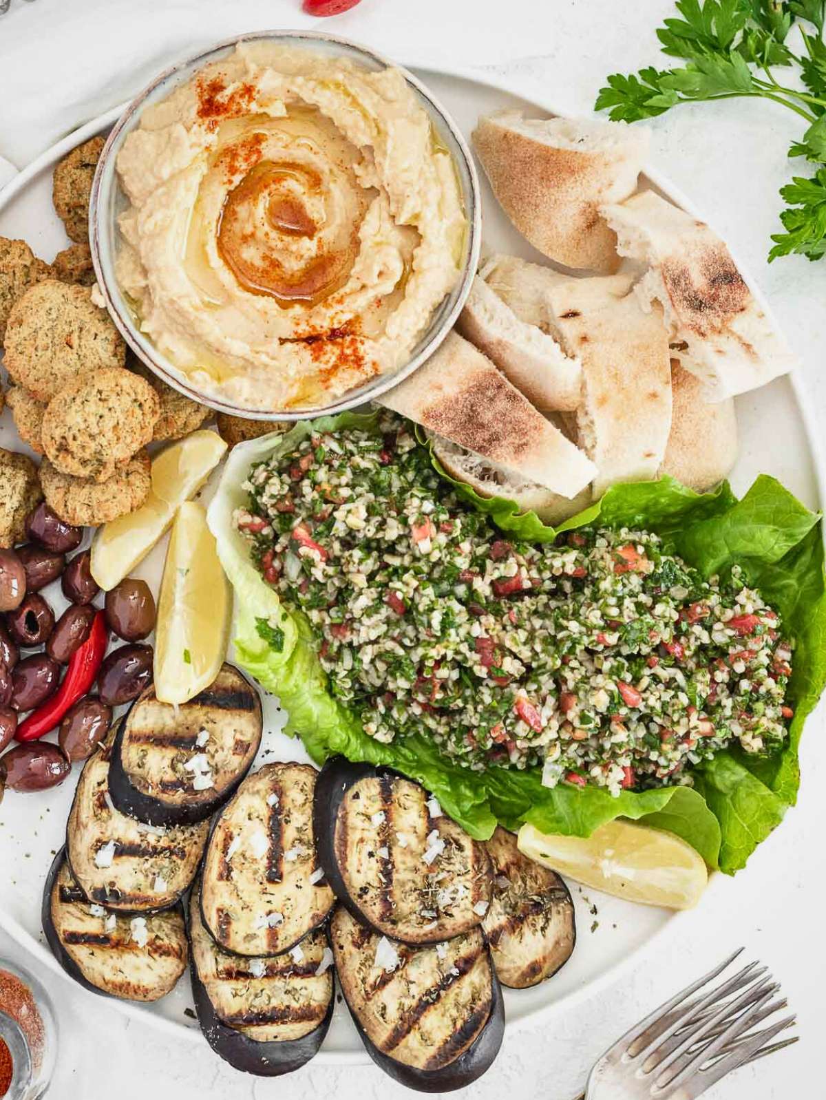 Tasty side dishes to serve with hummus on a white plate.