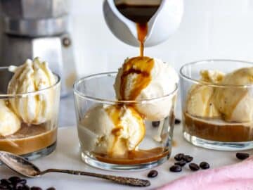 Pouring hot espresso coffee over two scoops of vanilla ice cream.