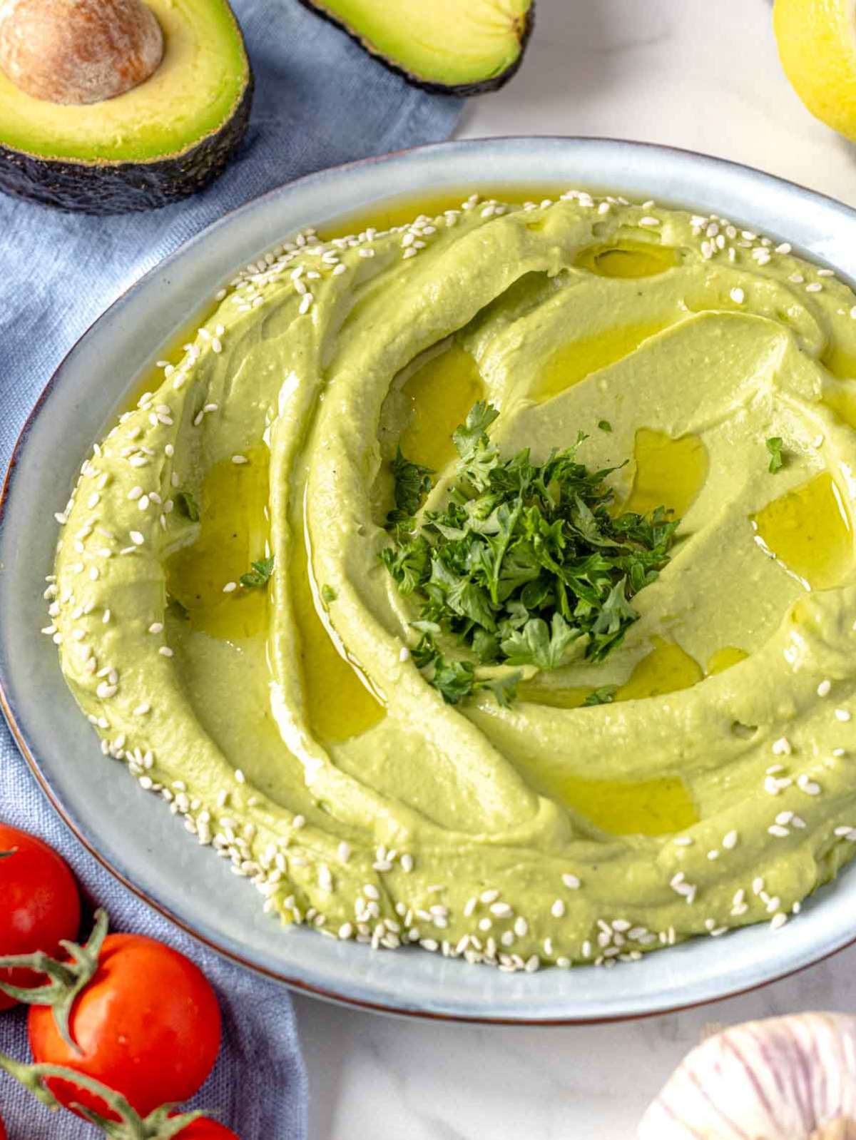 Avocado spread topped with olive oil, sesame seeds, and parsley.