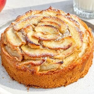 Baked whole vegan apple cake topped with overlapping cinnamon apple slices