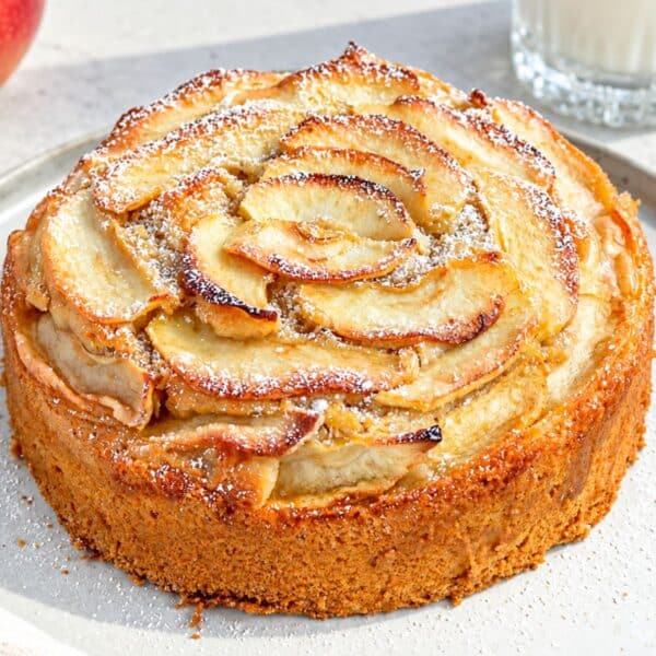Baked whole vegan apple cake topped with overlapping cinnamon apple slices