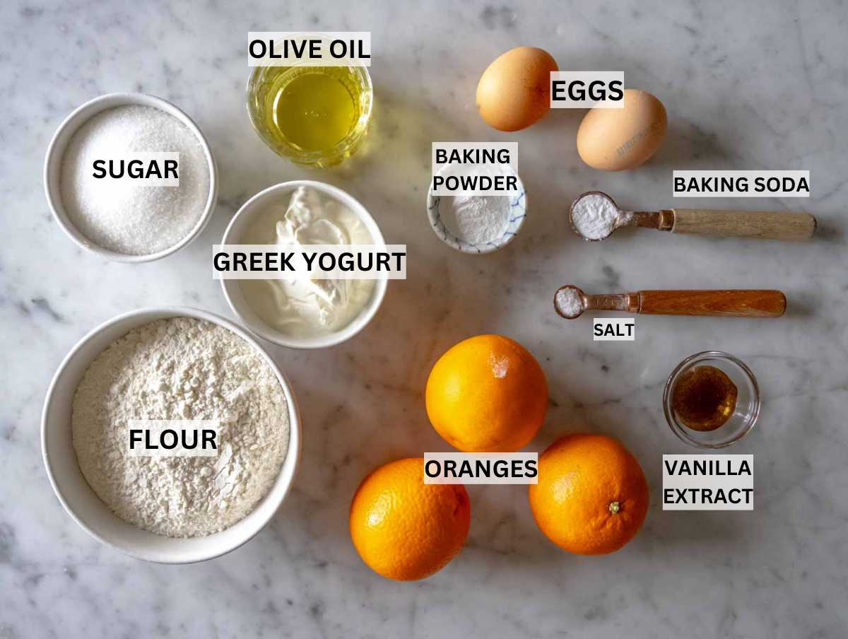 Ingredients for orange cake on a marble surface.