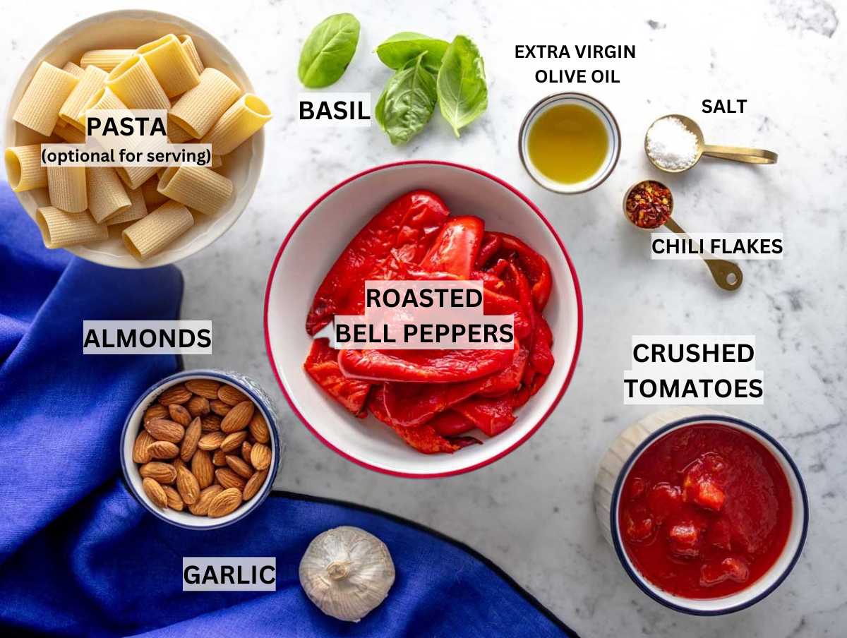 Ingredients for roasted red pepper sauce on a marble table.