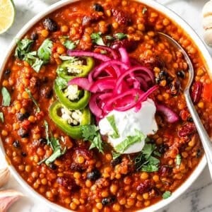 Lentil chili topped with cilantro, and Greek yogurt on Carrara marble.